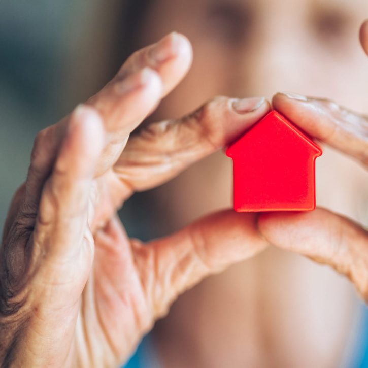 Les lois concernant le crédit immobilier en France et le prêt hypothécaire en Suisse Personne tenant une maison entre les mains représentant son emprunt immobilier.