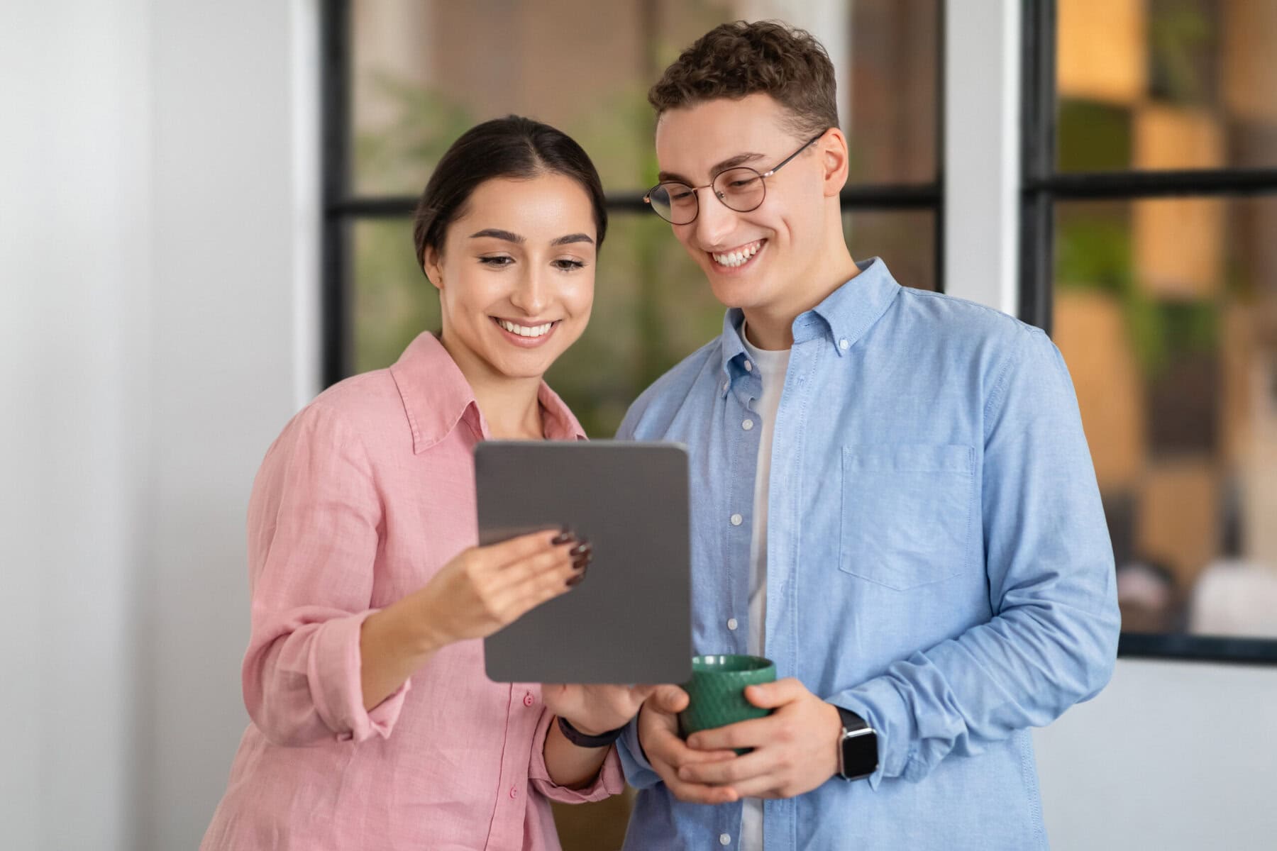 Smiling young arab lady shows tablet to european man manager Étude quasi-résident pour le frontalier en Suisse
